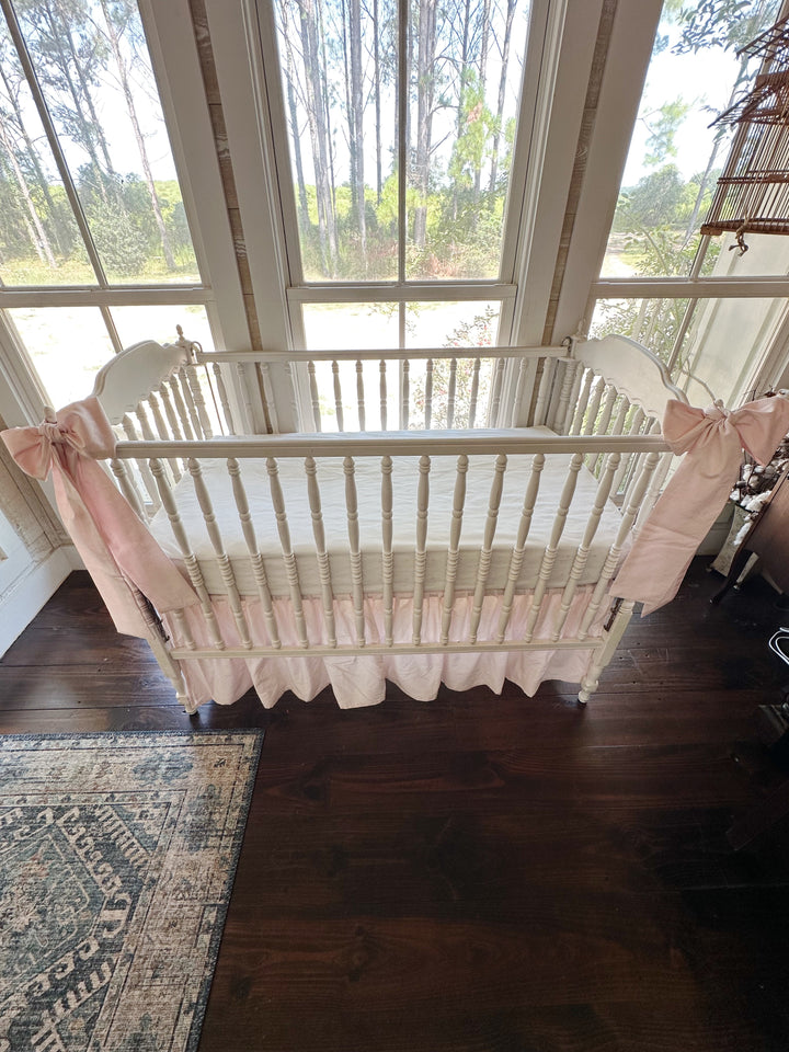 Overhead view of the whole crib showing both pink bows and the gathered baby pink skirt
