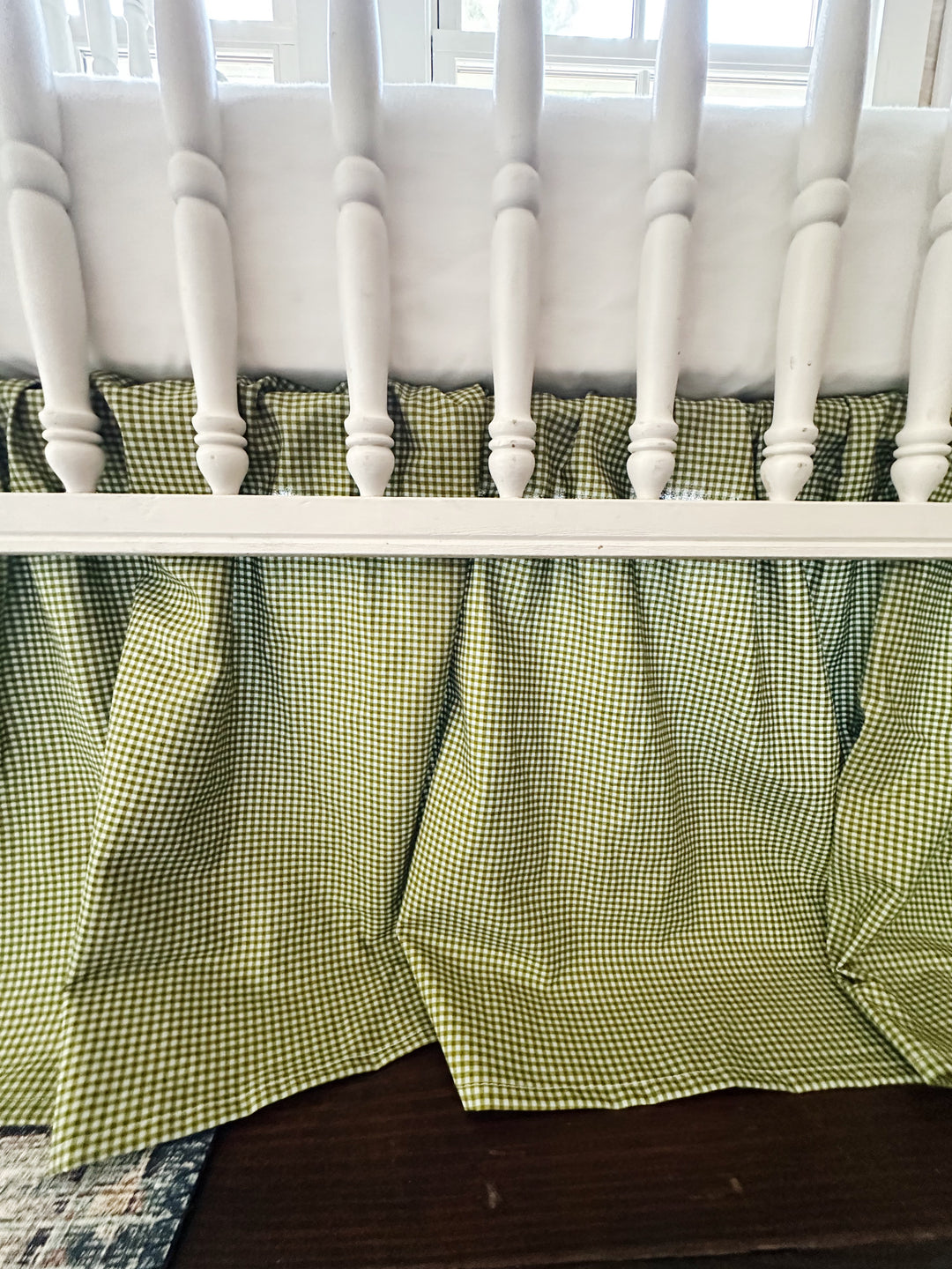 Gathered pleats and ruffle detail of the pine green gingham farmhouse crib skirt