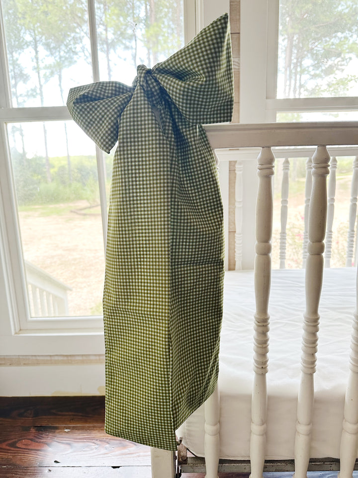 Pine green gingham crib bow tied on a white spindle crib rail in a farmhouse nursery