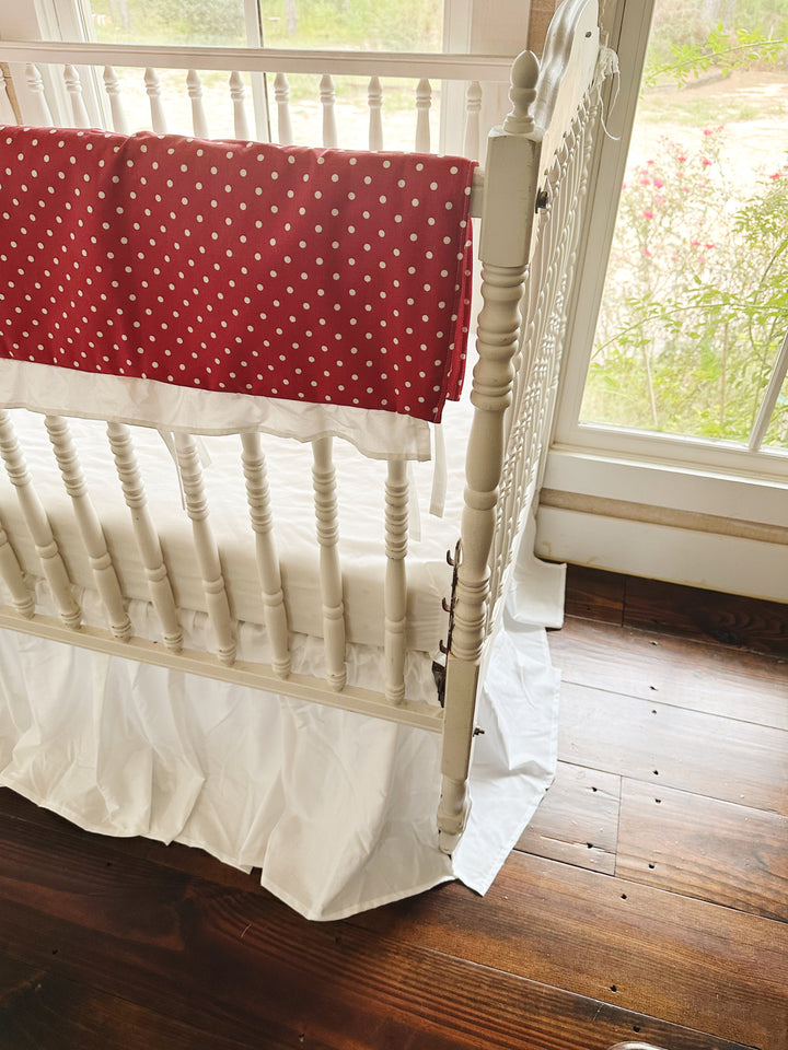 The red polka dot rail cover ending at the corner post above the white farmhouse skirt