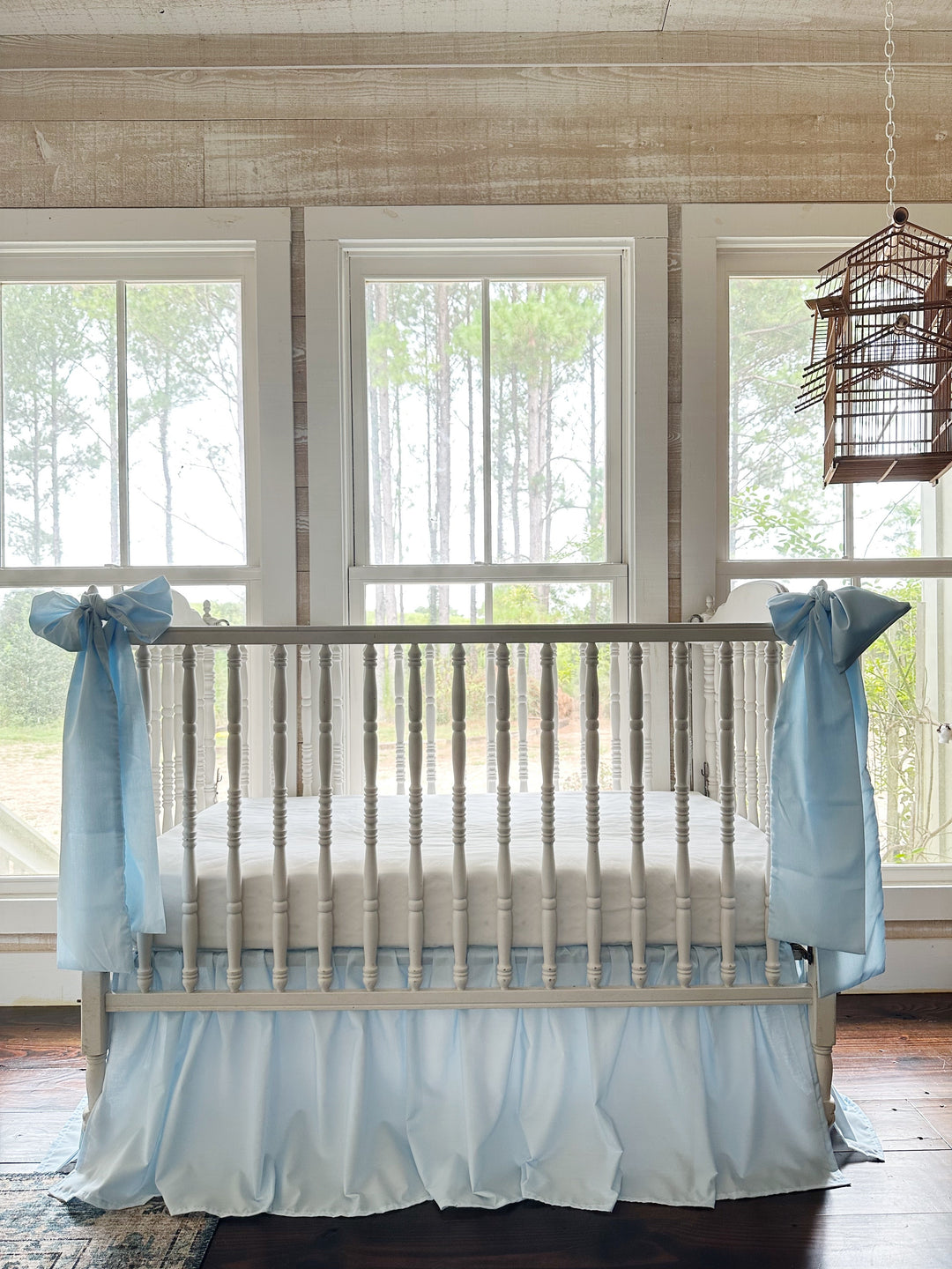 Heirloom blue farmhouse crib skirt with two large blue bows tied at the crib corner posts