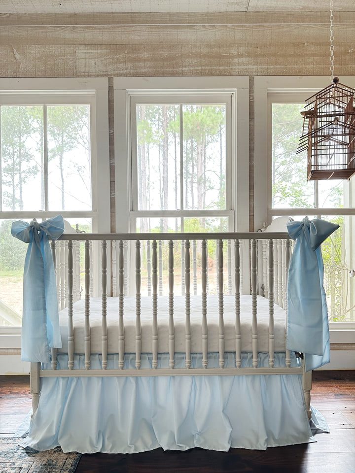 Heirloom blue farmhouse crib skirt with two large blue bows tied at the crib corner posts