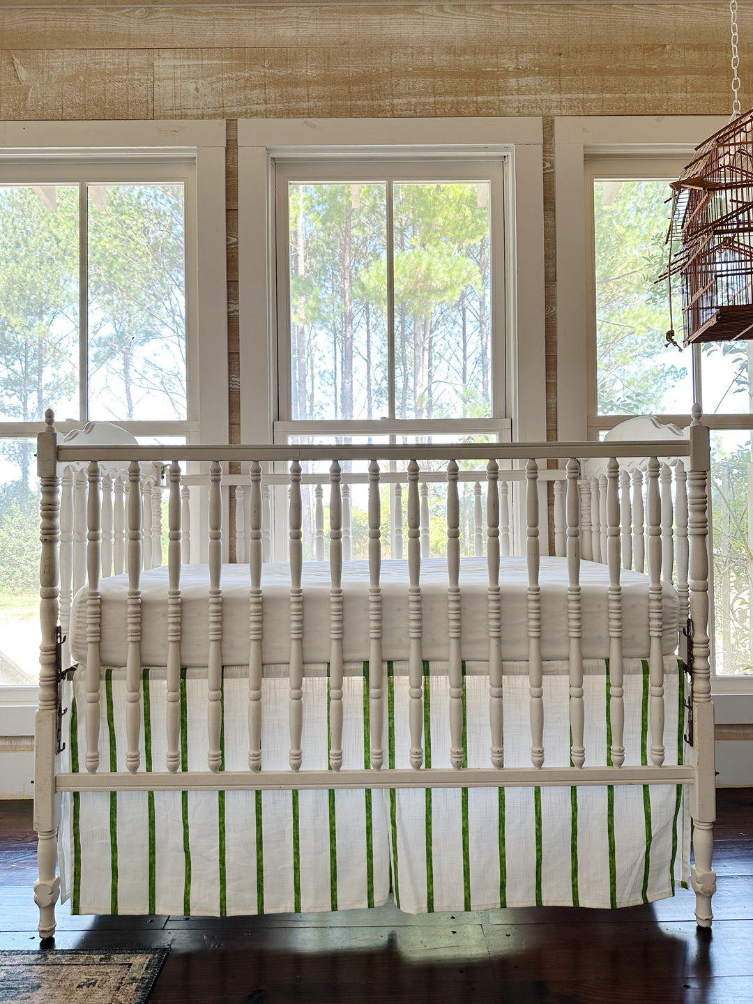 Cypress green and white striped tailored crib skirt on a white spindle crib, pleated panels and a 20-inch drop