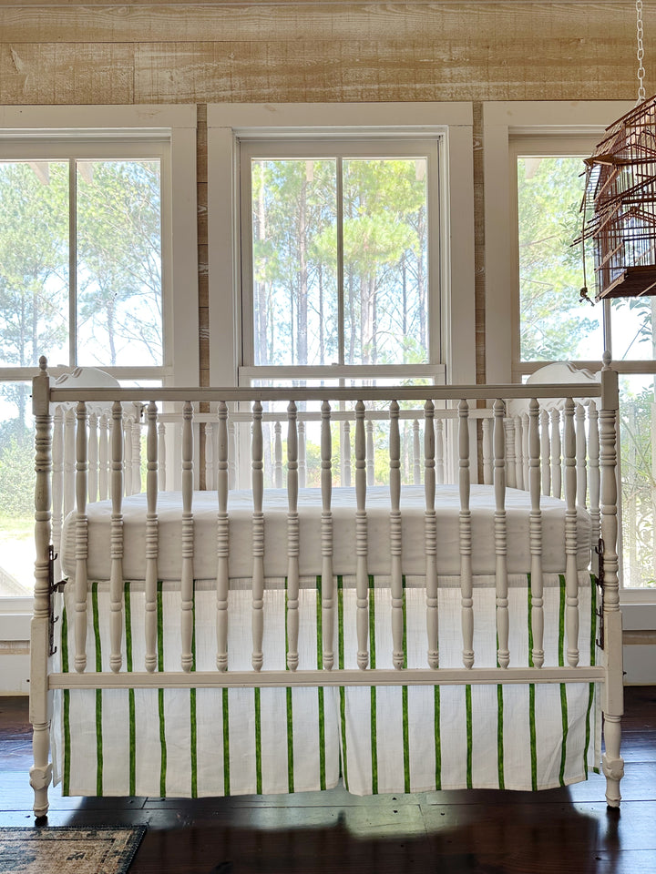 Cypress green and white striped tailored crib skirt on a white spindle crib, pleated panels and a 20-inch drop