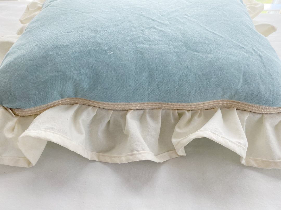 Detail of the hidden zip closure along the edge of the mist and ivory crib pillow