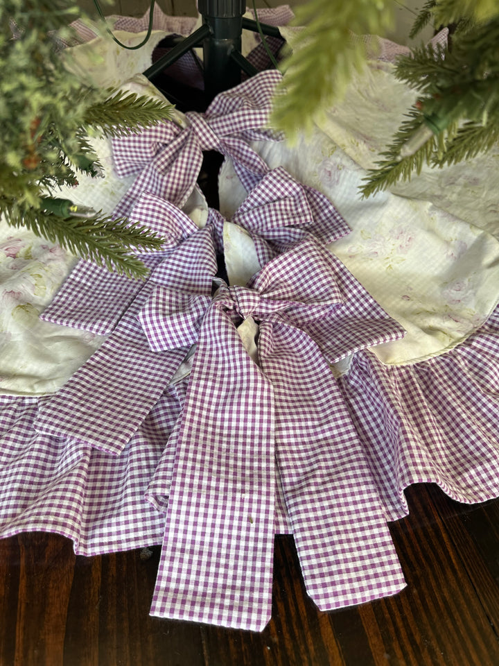 Three big lavender gingham bows tied down the center opening of the floral tree skirt, around a tree stand