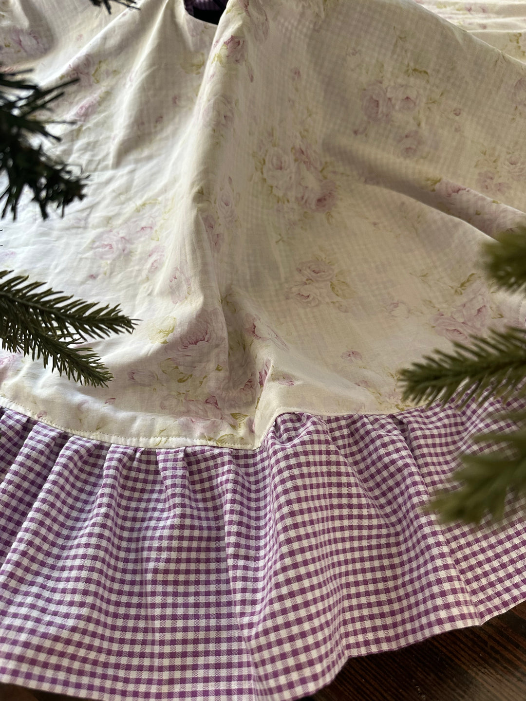 Close-up of watercolor lavender roses on cream cotton meeting the gathered lavender gingham ruffle
