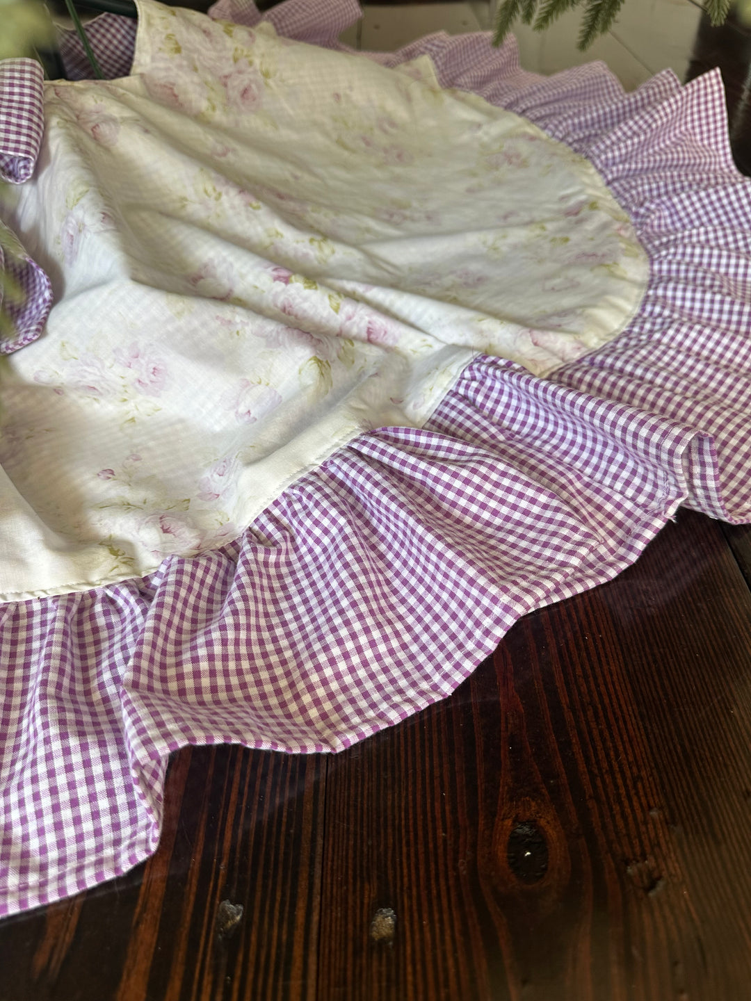 Wide lavender gingham ruffle fanned out on a wood floor around the shabby chic floral center