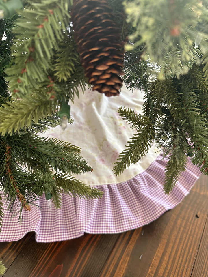 Pinecone ornament hanging over the cream floral tree skirt and its lavender gingham ruffle