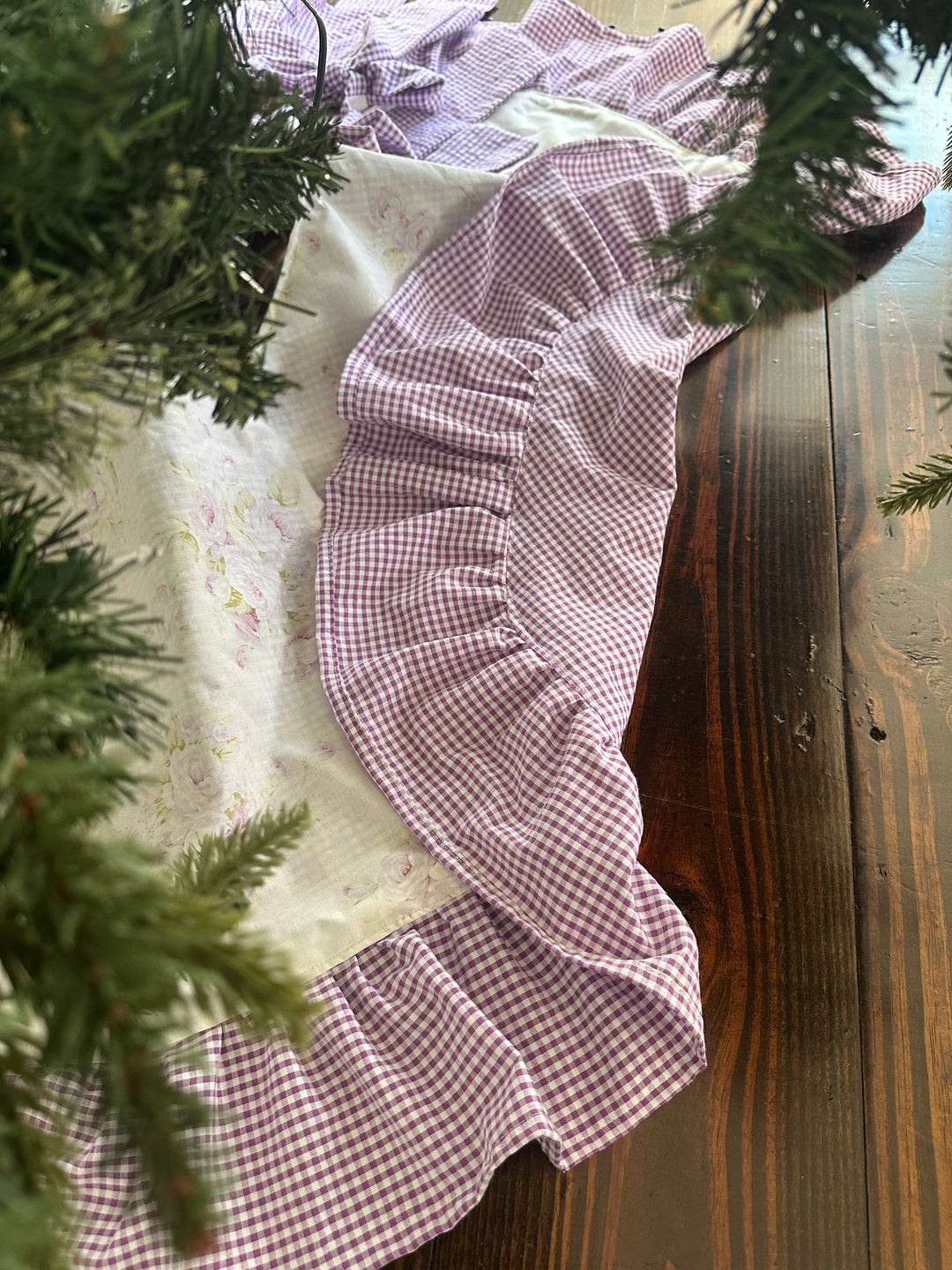Edge of the tree skirt folded back to show the full lavender gingham lining beside the shabby chic floral front
