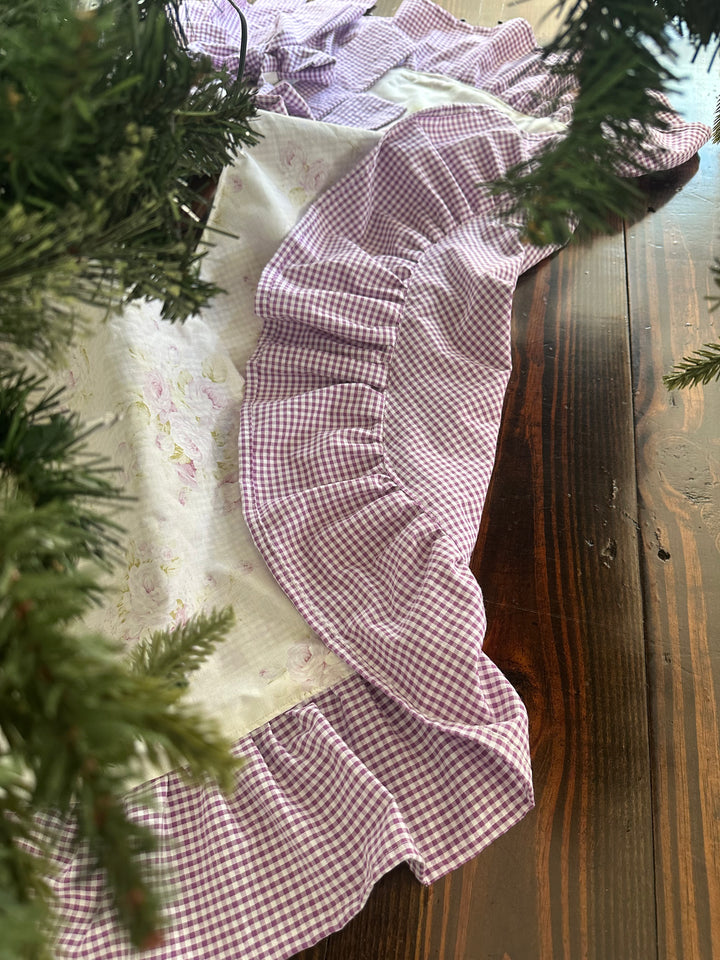 Edge of the tree skirt folded back to show the full lavender gingham lining beside the shabby chic floral front