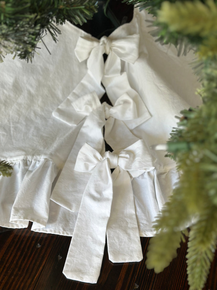 Close-up of three stacked white bows closing the front of the cotton tree skirt above the gathered ruffle