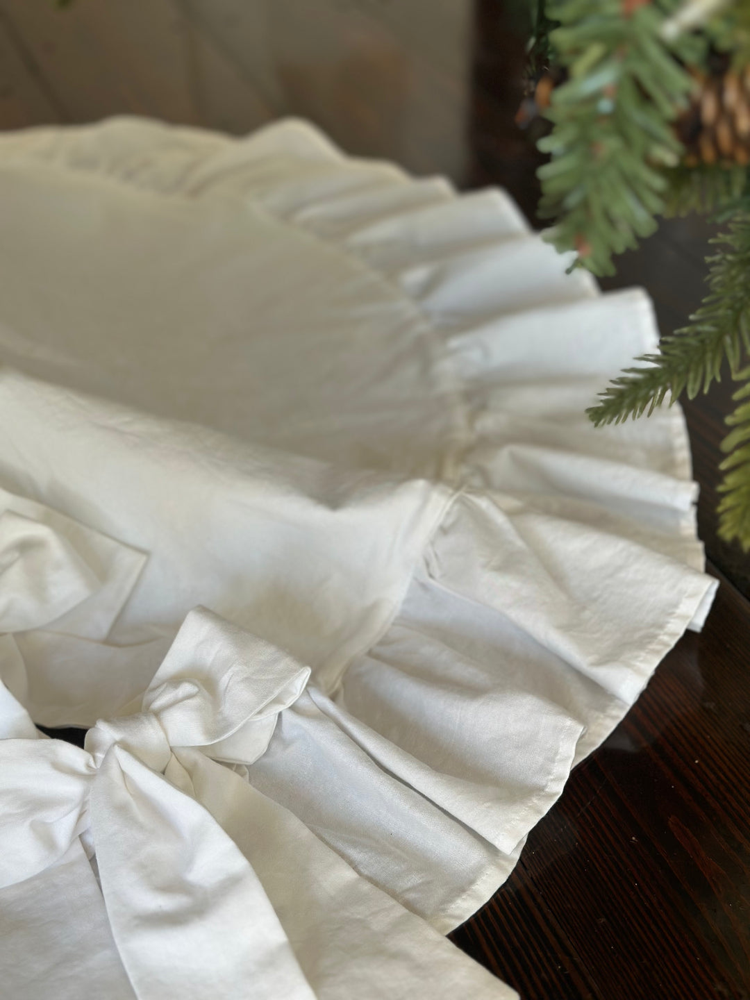 White bow tie resting on the gathered ruffle edge of the round cotton tree skirt
