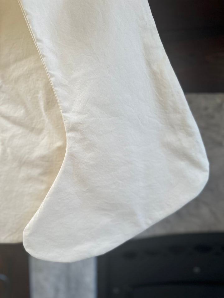 Detail of the curved toe and washed cotton texture on an ivory Christmas stocking