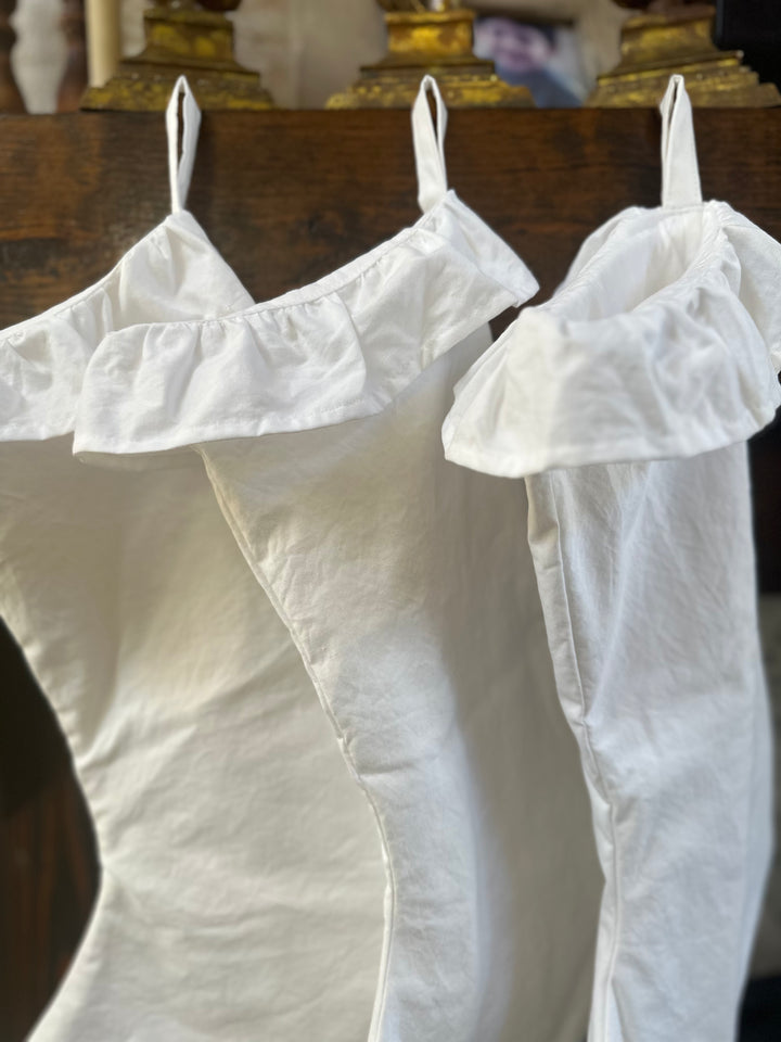 White ruffled cuffs and slim cotton hanging loops on stockings hung from the mantel