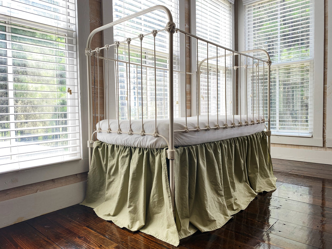 Sage green 4-sided gathered crib skirt on antique white iron crib, full front view, washed cotton nursery bedding