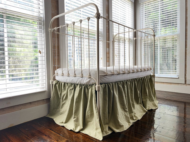 Sage green 4-sided gathered crib skirt on antique white iron crib, full front view, washed cotton nursery bedding