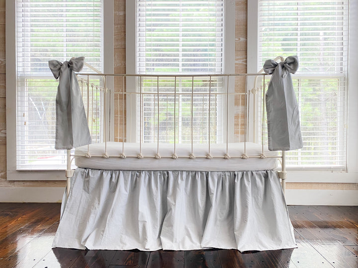 Zen grey gathered crib skirt and matching large crib bows on white iron farmhouse crib, front view, handmade in Alabama