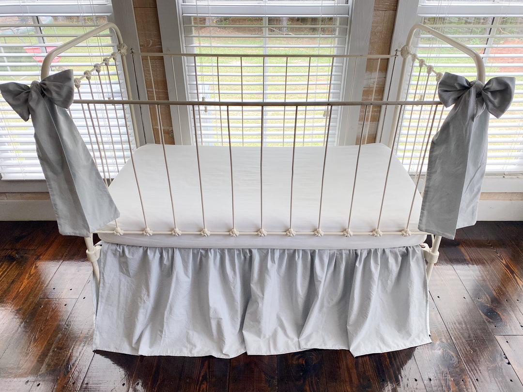 Zen grey crib skirt and large crib bow set, three-quarter angle view showing all-sided coverage on iron crib