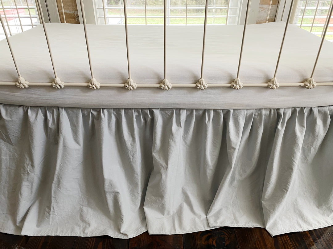 Close-up front detail of zen grey gathered crib skirt ruffle at mattress level, washed cotton farmhouse nursery
