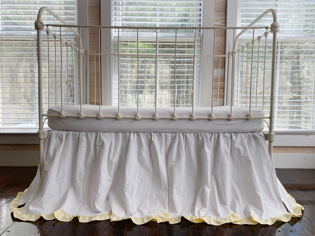 White gathered crib skirt with yellow ruffle hem on antique iron crib, full front view, 22 inch drop heirloom bedding