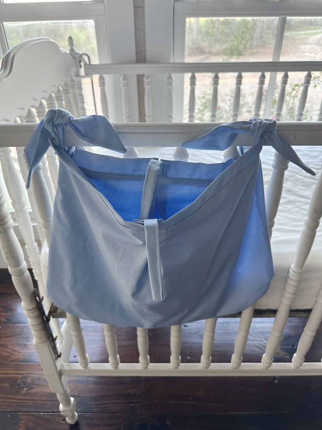 Baby blue crib caddy open at the top, showing the deep pouch and the center tie strap