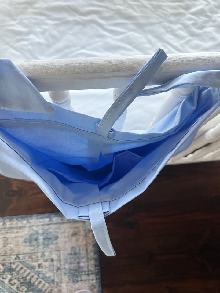 Looking down into the baby blue caddy's deep cotton pouch from above the crib rail