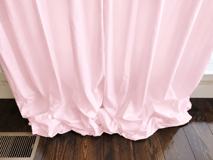 Close view of the baby pink farmhouse curtain hem gathered on the floor, showing the weight of the lined cotton - High Cotton Textile