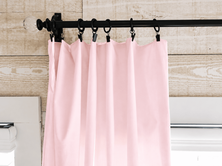 Black clip rings holding the flat top edge of the baby pink farmhouse curtain panels against shiplap - High Cotton Textile