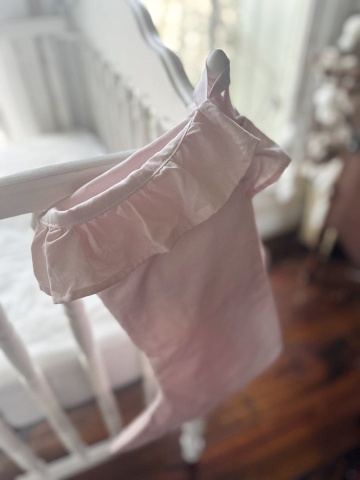 Close view of a baby pink stocking cuff ruffle and hanging loop on a crib