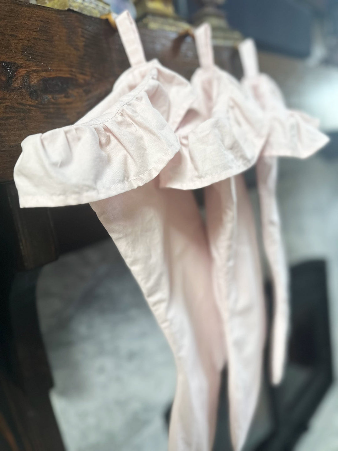 Baby pink stockings hanging long from a mantel, showing the full stocking length