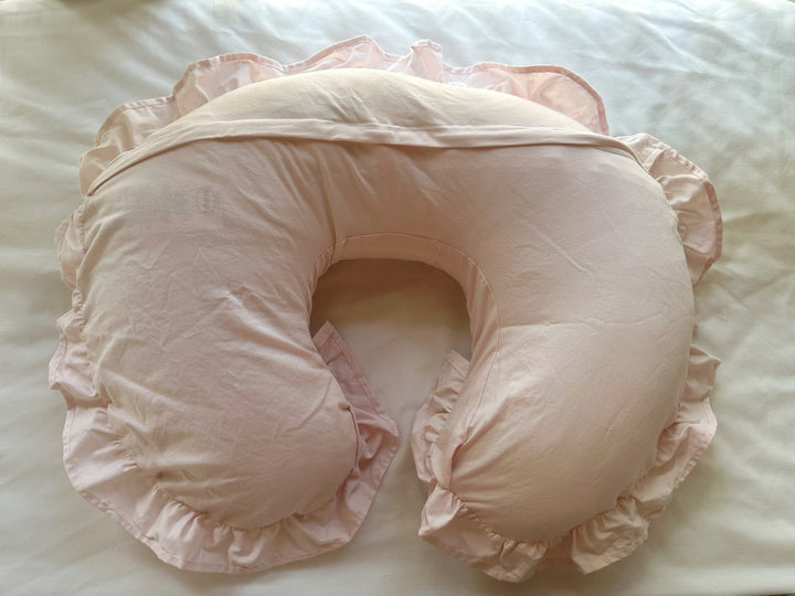 Baby Pink Boppy cover from the back on white bedding, with the envelope flap closure running along the top