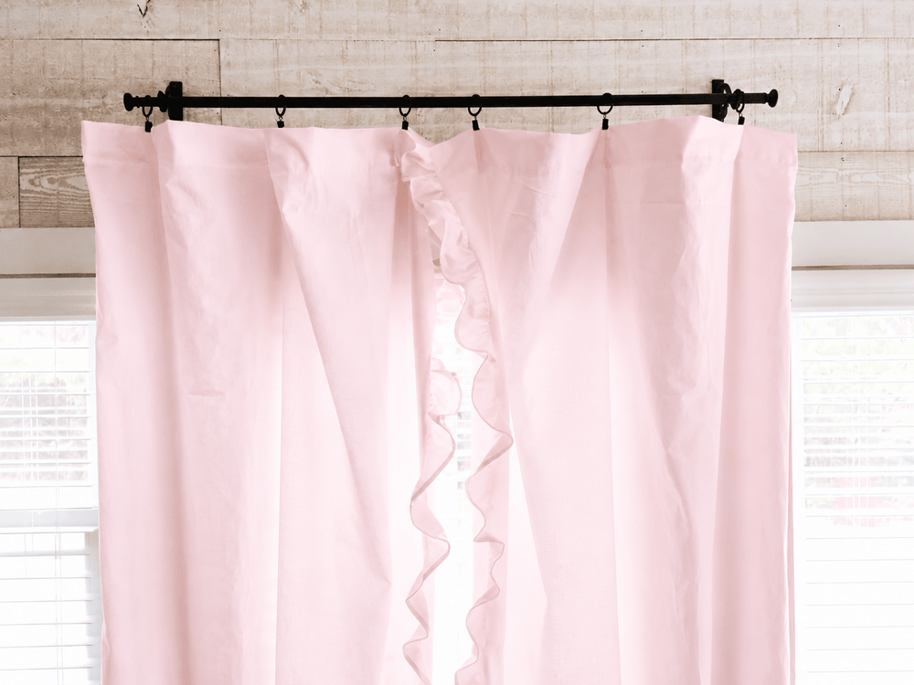 Top of the baby pink ruffled curtain panels on iron rings, showing the gathered heading against shiplap - High Cotton Textile