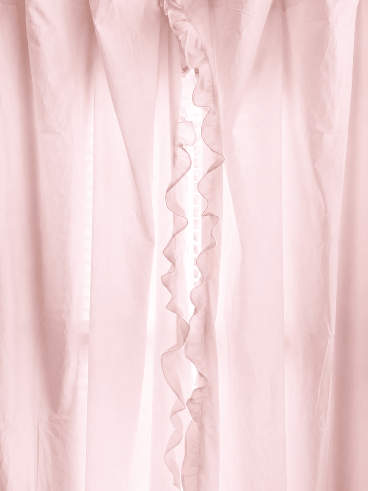 Baby pink ruffled curtain panels parted at the center, the ruffle running the full length of the leading edge - High Cotton Textile