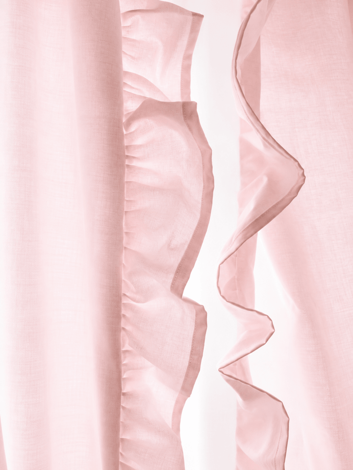 Close view of the ruffle on the leading edge of a baby pink curtain panel, backlit so the washed cotton weave shows - High Cotton Textile
