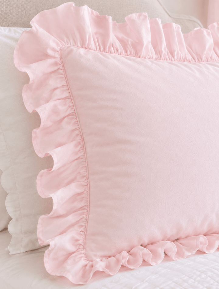Close up of the gathered ruffle edge and washed cotton face of a baby pink pillow sham - High Cotton Textile