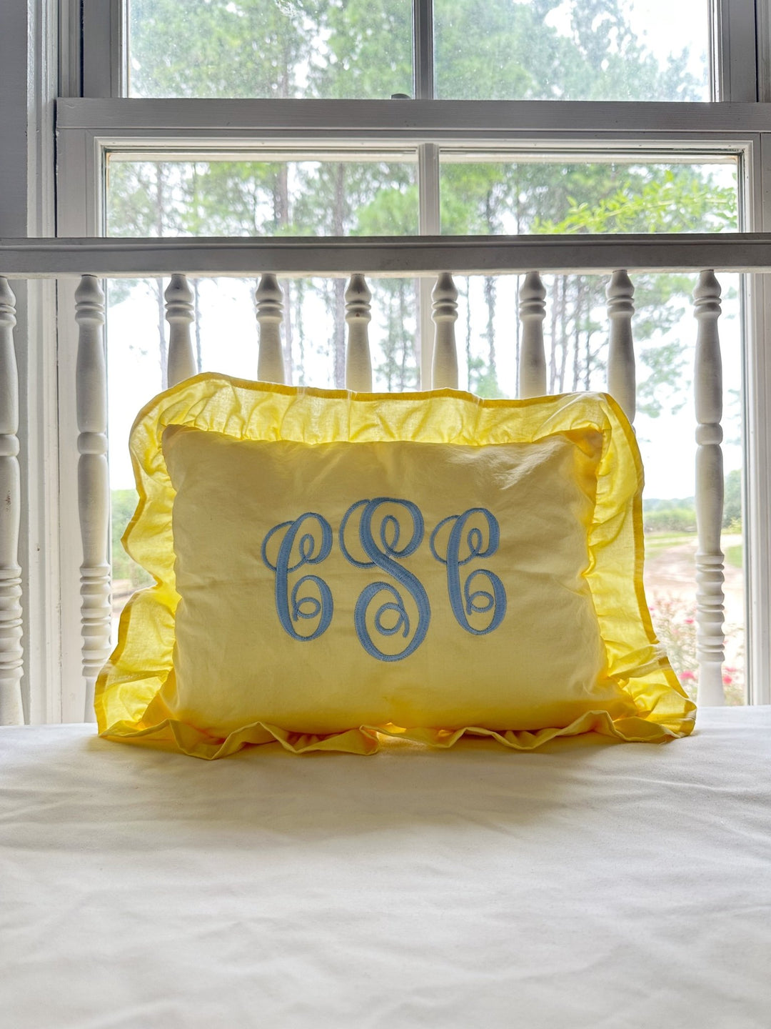 Monogrammed baby yellow ruffled nursery pillow in washed cotton styled by a sunny window - High Cotton Textile