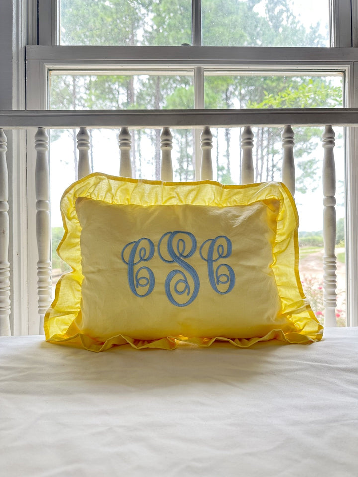 Monogrammed baby yellow ruffled nursery pillow in washed cotton styled by a sunny window - High Cotton Textile