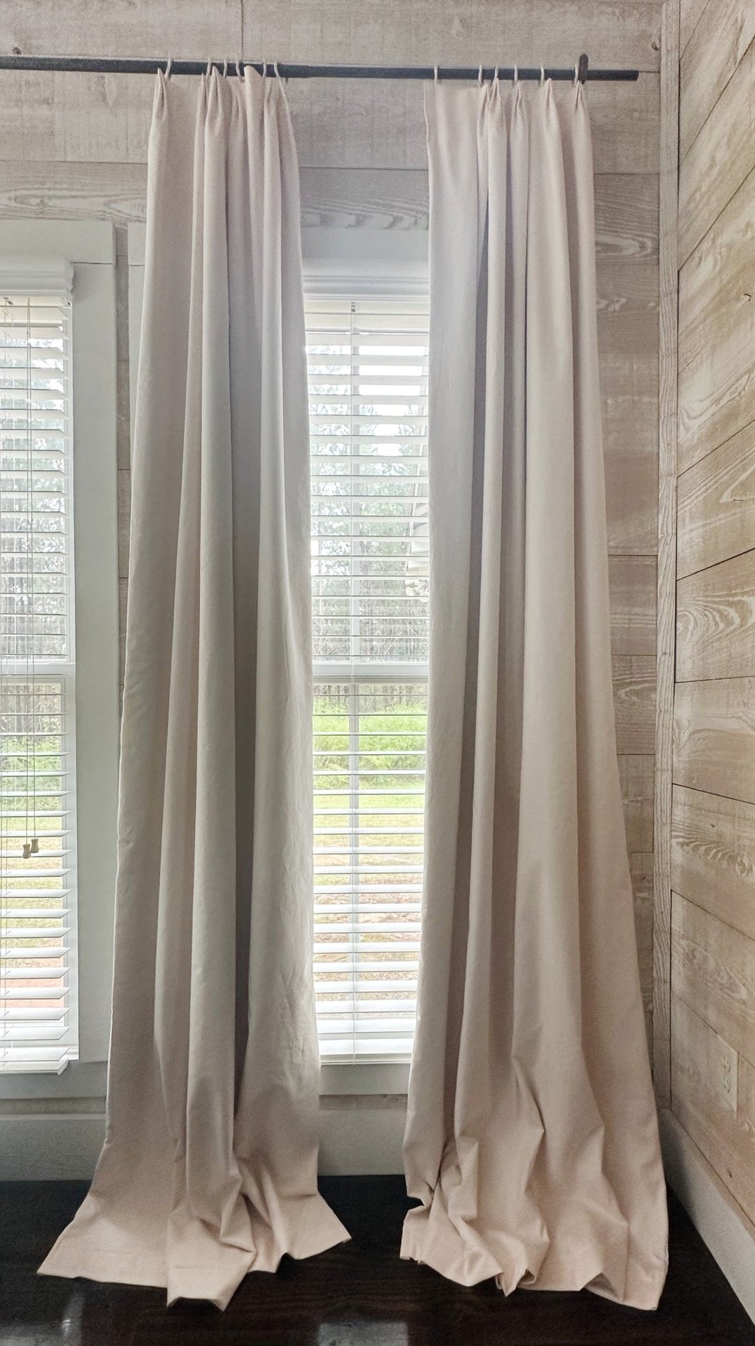 Full-length Ballet Slipper Pink euro pleat blackout curtains on either side of a window in a room with plank walls