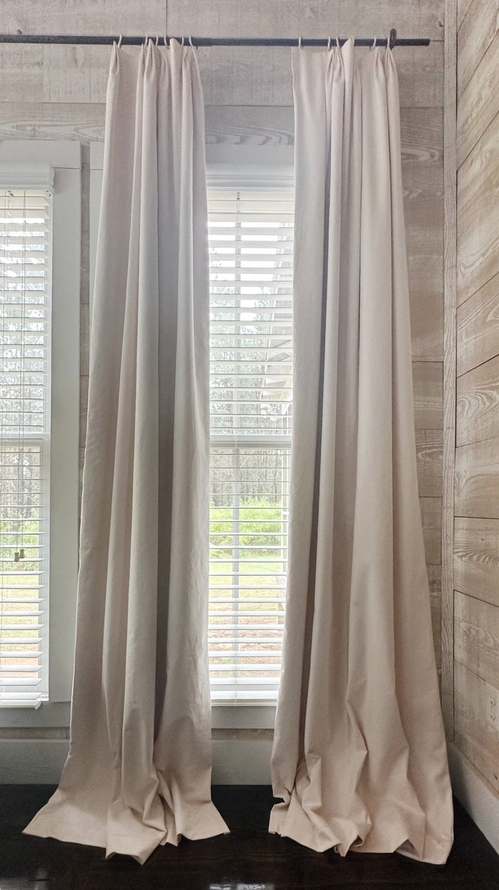 Pair of Ballet Slipper Pink euro pleat blackout curtain panels on a black iron rod, framing a window and puddling on a dark wood floor