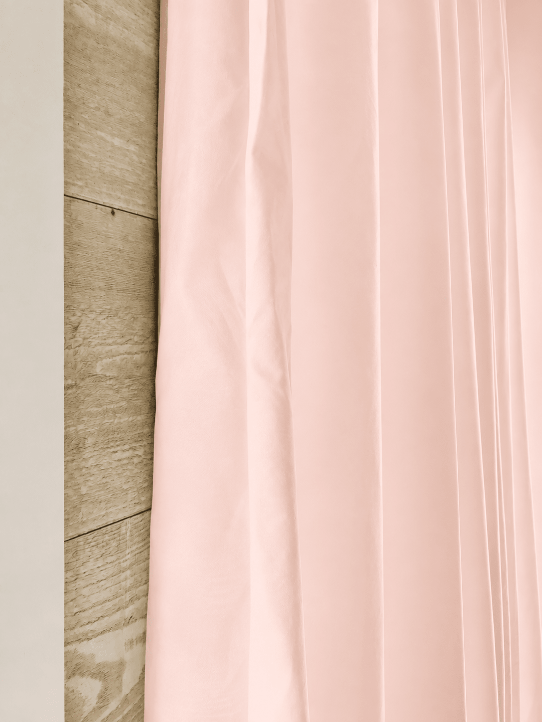 Edge of a Ballet Slipper Pink farmhouse curtain panel against pale shiplap, showing the peachy undertone in the washed cotton - High Cotton Textile