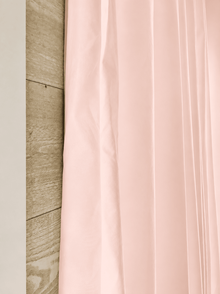Edge of a Ballet Slipper Pink farmhouse curtain panel against pale shiplap, showing the peachy undertone in the washed cotton - High Cotton Textile