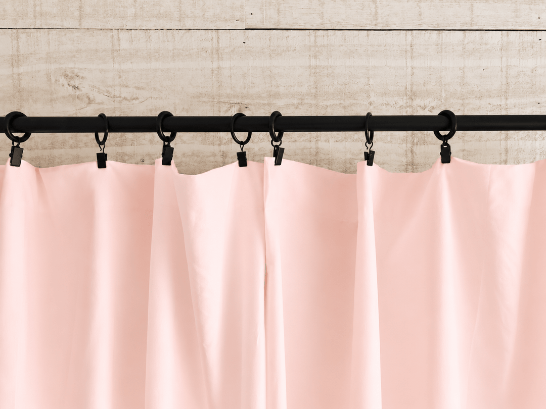 Black clip rings holding the flat top edge of the Ballet Slipper Pink farmhouse curtain panels against shiplap - High Cotton Textile