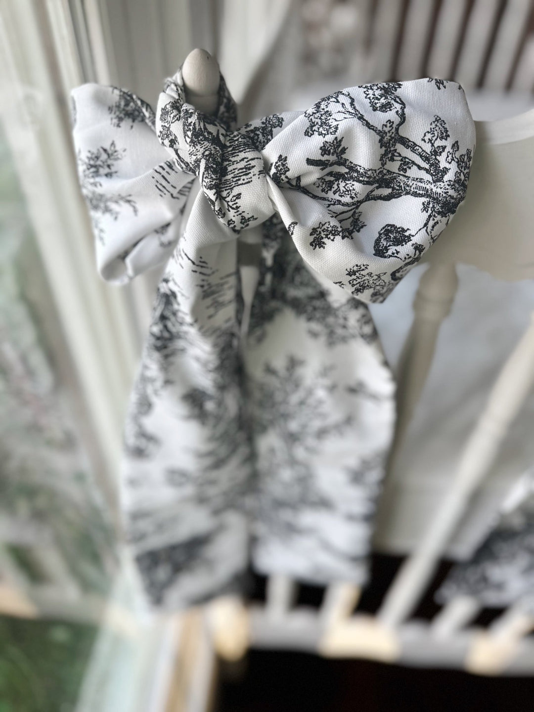 Black toile bow knotted on a crib post, angled view