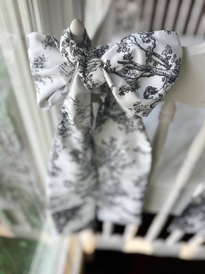 Black toile bow knotted on a crib post, angled view