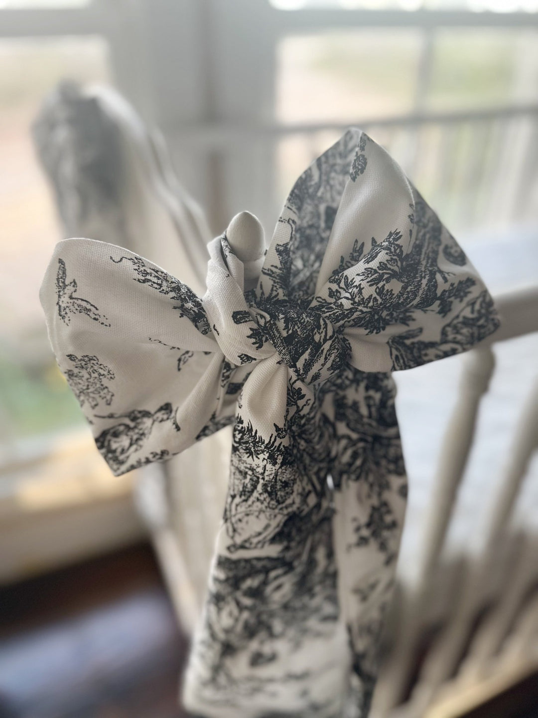 Close view of a black and white toile bow showing the pastoral print