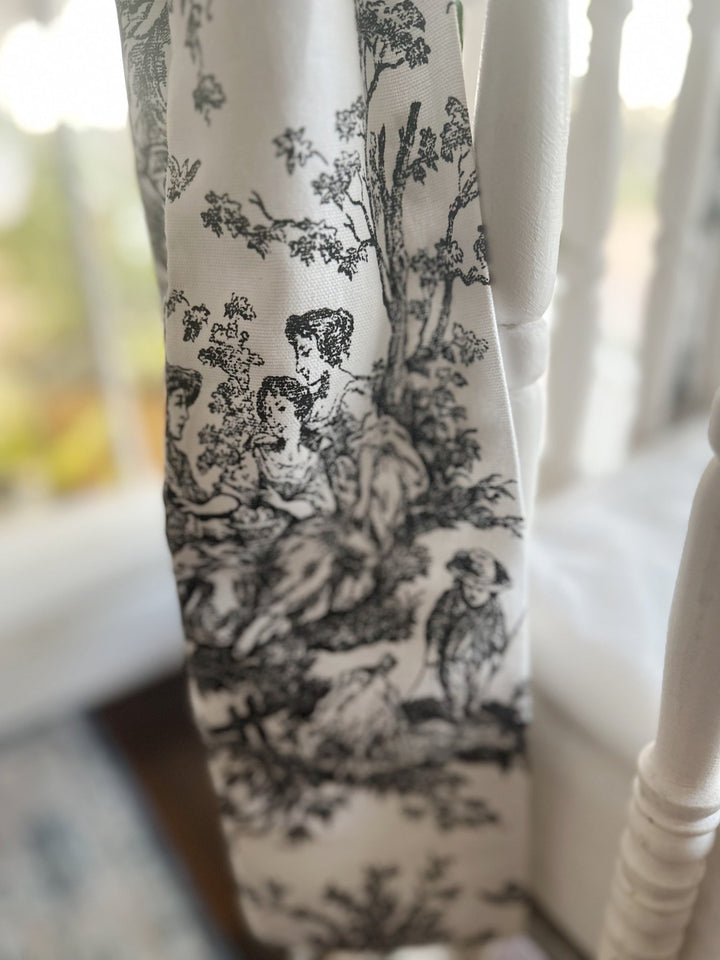 Detail of the black and white toile print on the bow tail, showing trees and figures