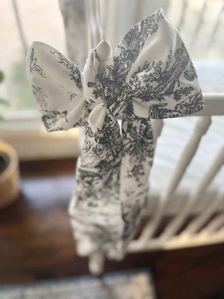 Soft cotton toile bow loops on a white crib finial