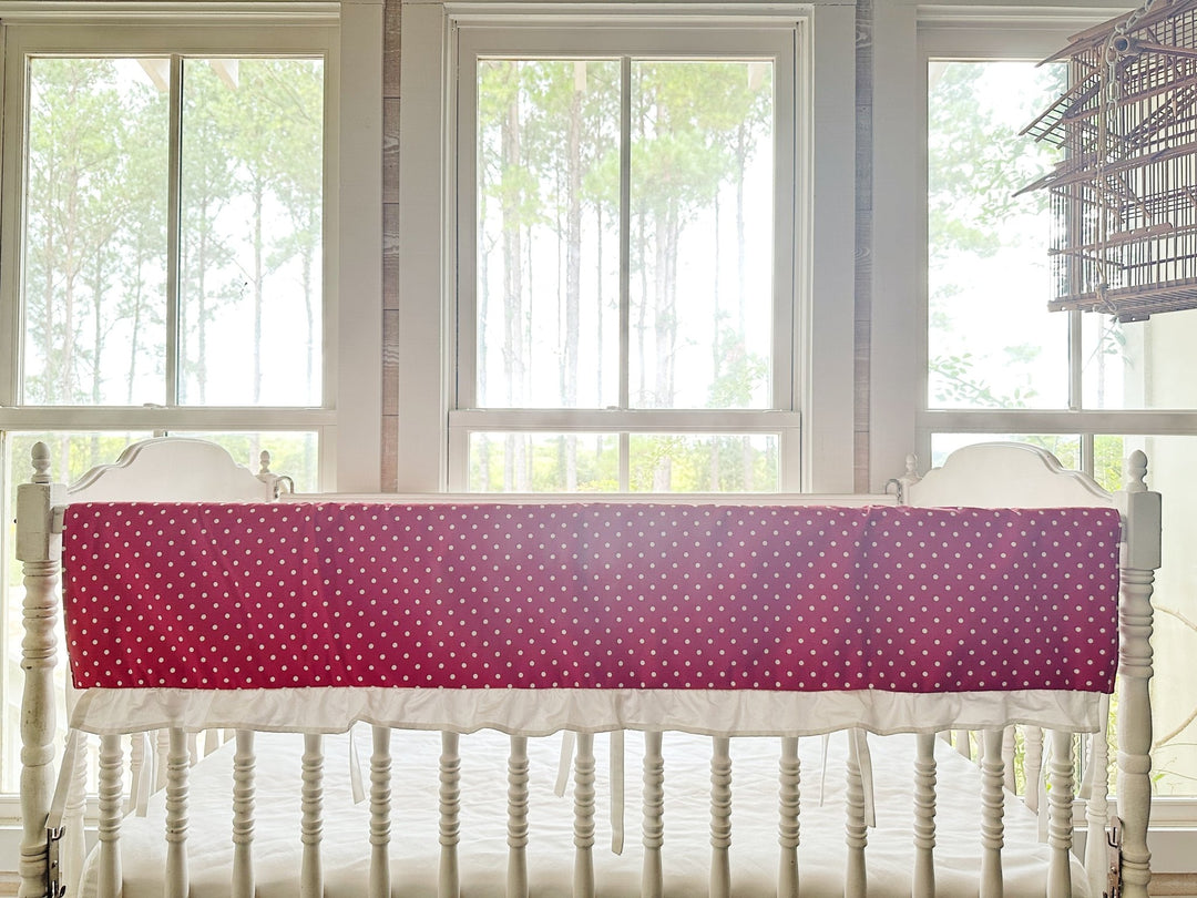 The polka dot rail cover seen straight on with its white ruffle and slim ties between the spindles