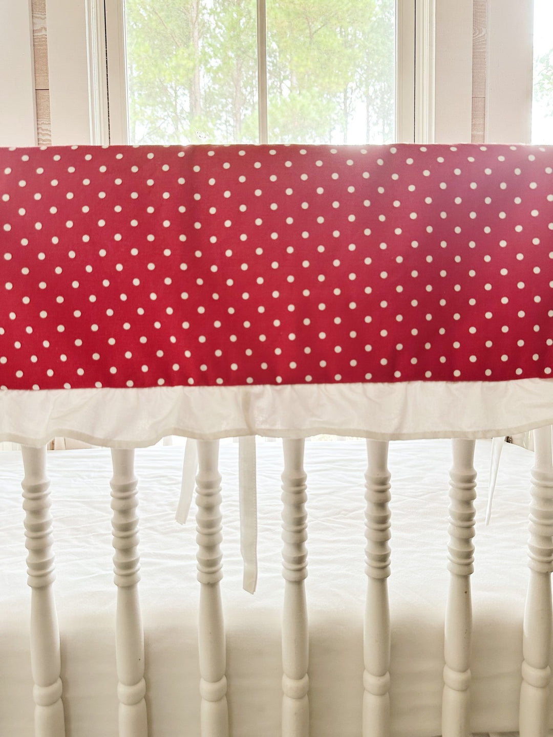 Close view of the small white dots on deep cherry red cotton above the gathered white ruffle